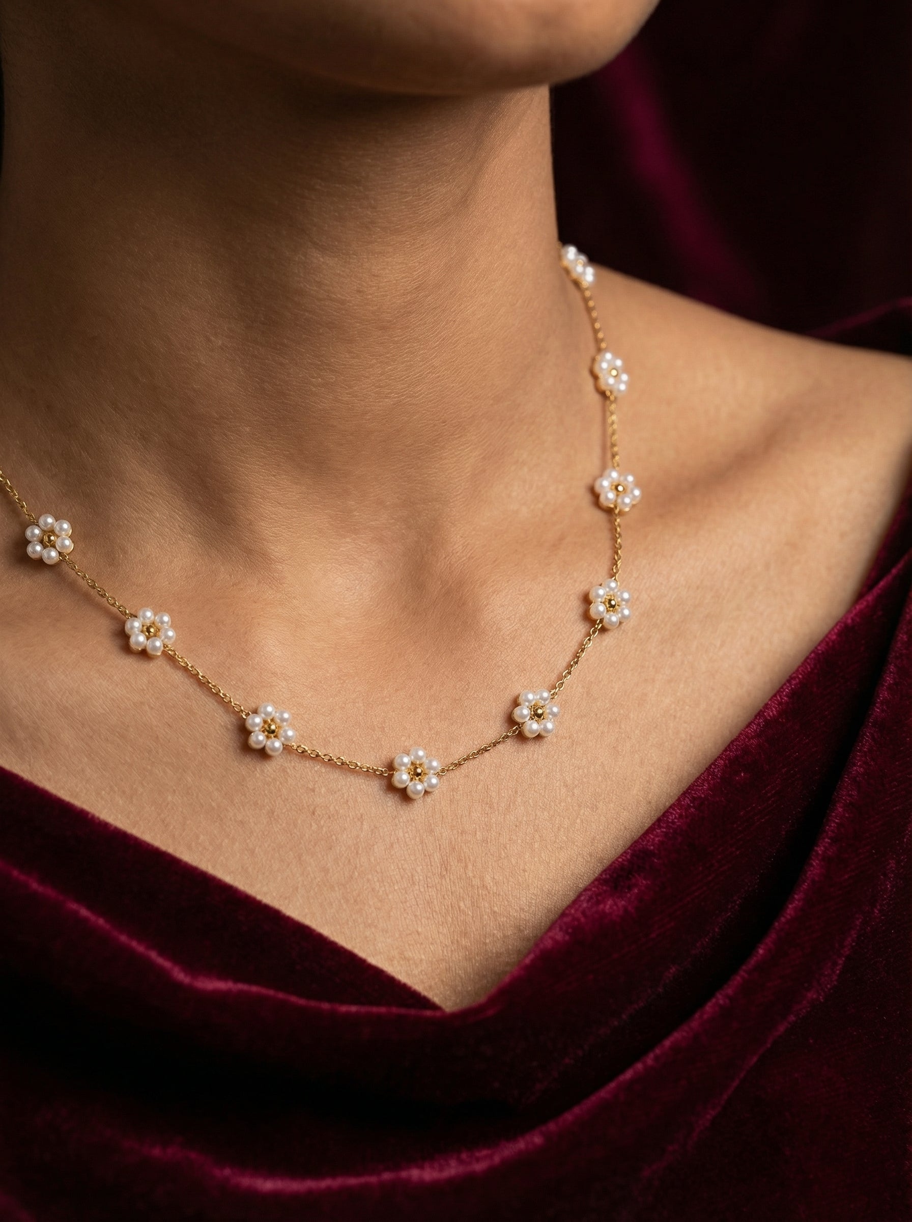 Necklace with floral pendants worn by a person against a dark background