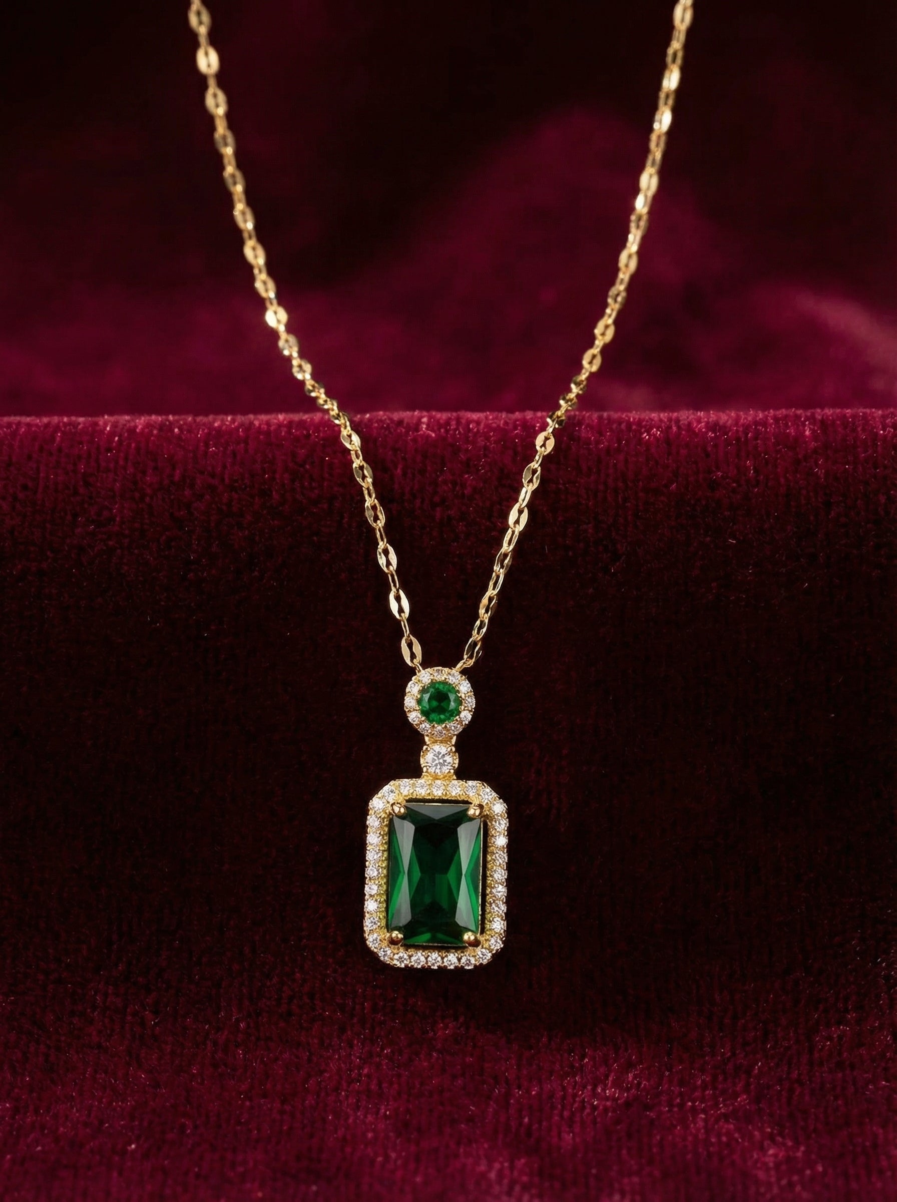 Gold necklace with a green gemstone pendant on a red velvet background
