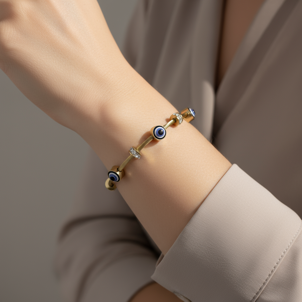 Close-up of a model's wrist wearing the Gold-Tone Evil Eye Cable Bangle with Crystal Accents on a minimalist background.