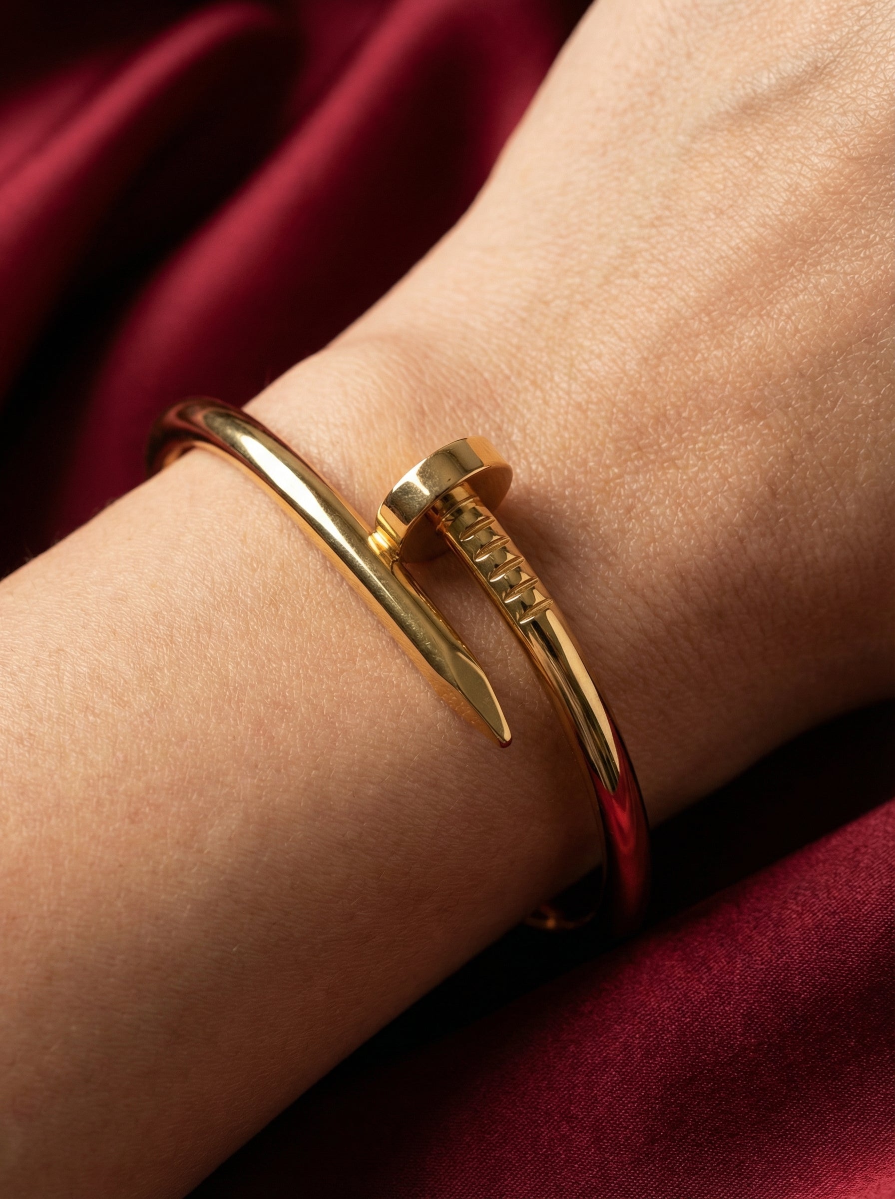 Gold bracelet on a wrist with a red fabric background