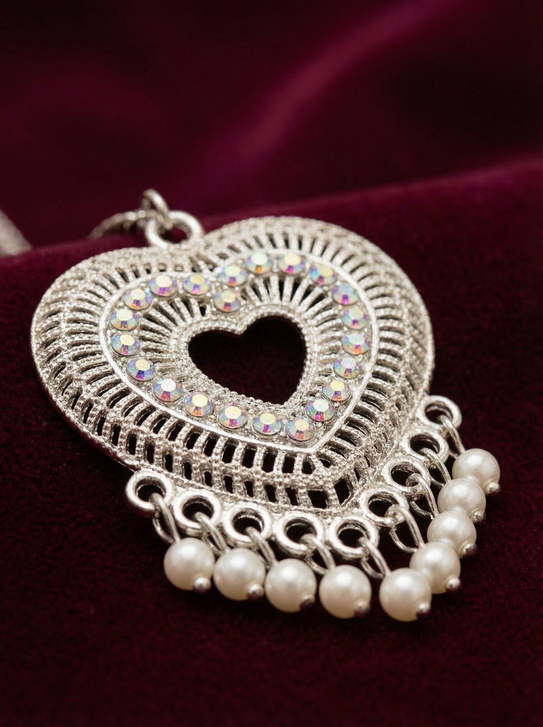 Heart-shaped pendant with rhinestones and pearls on a dark background