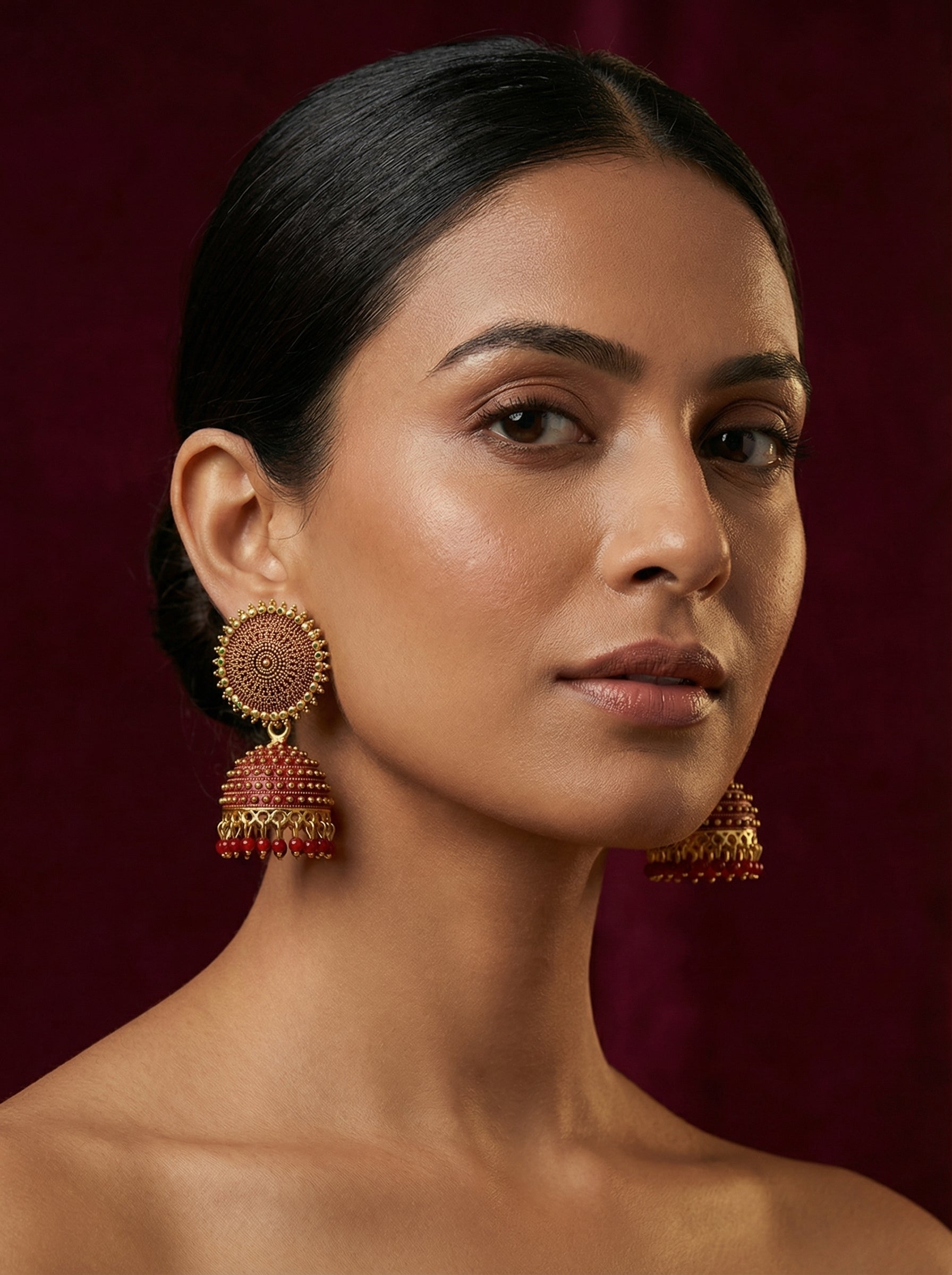 Woman wearing large, ornate earrings against a dark background